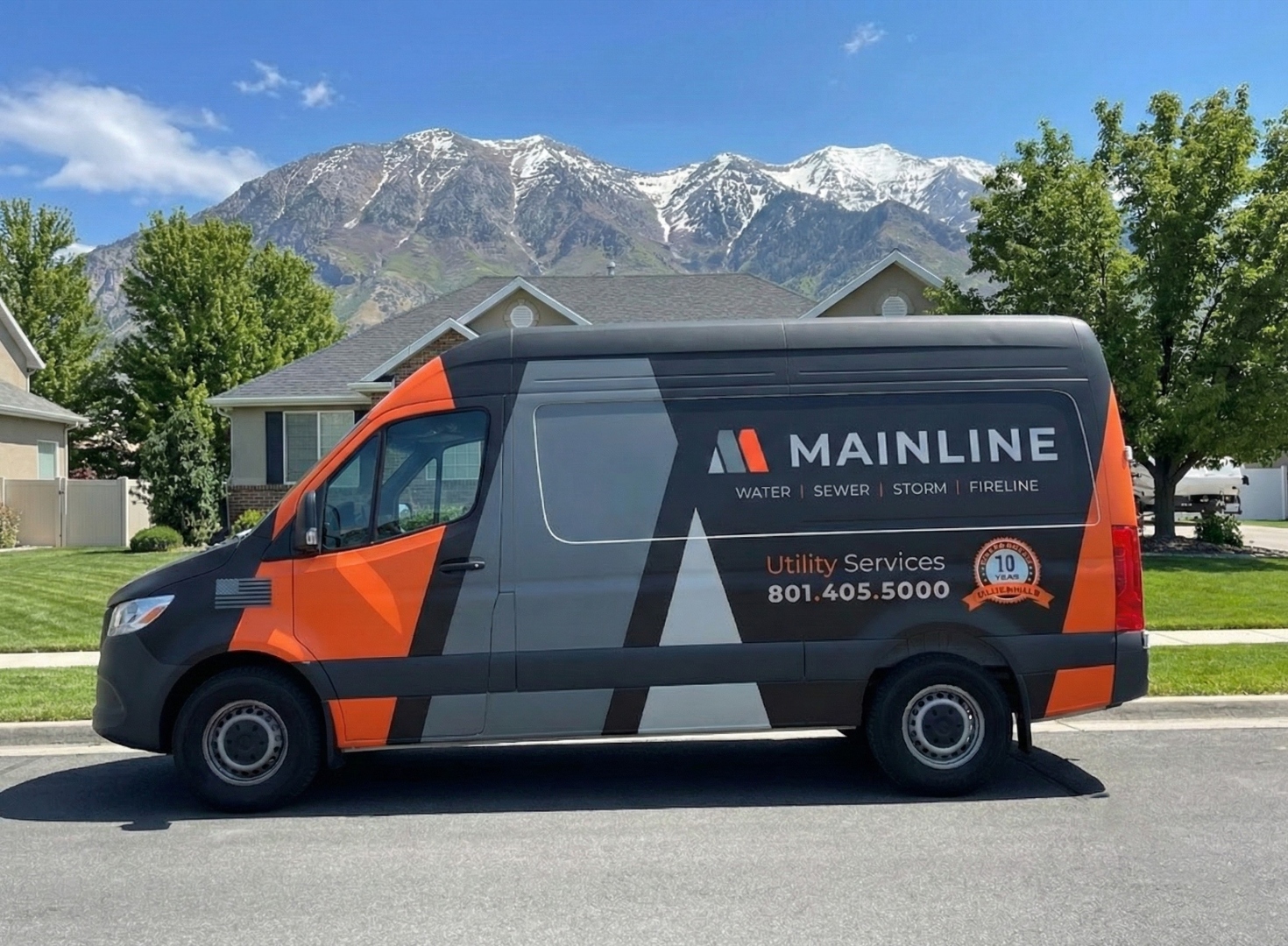 MAINLINE branded service van parked in front of a Utah home with the Wasatch Mountains behind it